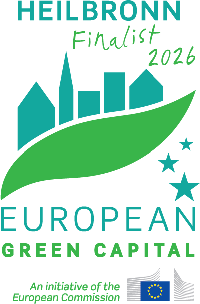 Offizielles Logo für Finalist:innen als European Green Capital. Zu sehen ist im oberen Bildteil ein geschwungenes grünes Blatt. Oberhabl des Blatts sind türkisfarbene Häuser abgebildet, unterhalb Sterne in der selben Farbe. Darum herum stehen die Schriftzüge Heilbronn Finalist 2026, European Green Capital und An initiative of the European Commission. Unten Rechts im Bild ist die Flagge der Europäischen Union abgebildet.